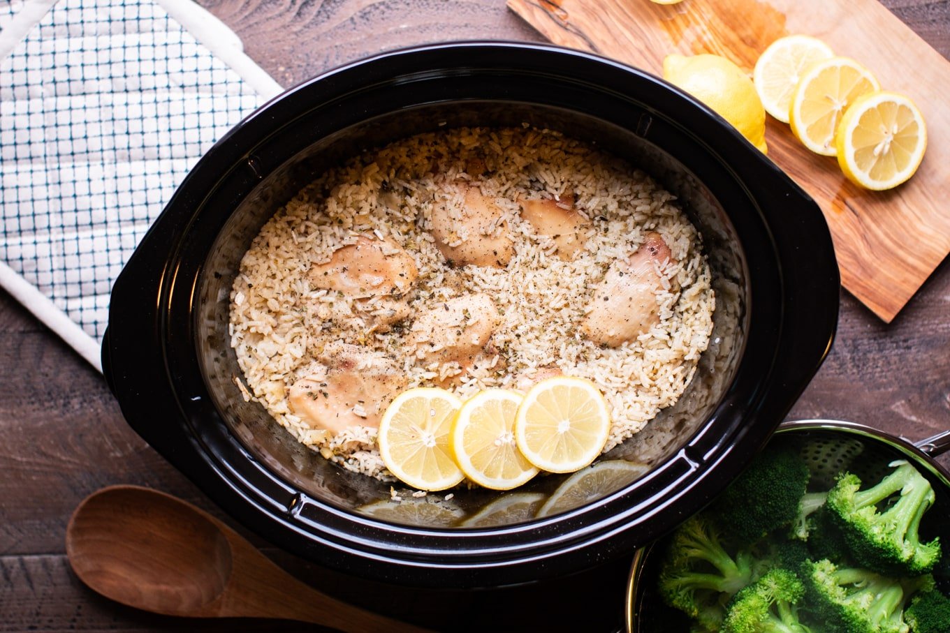 cooked lemon chicken and rice in slow cooker with wooden spoon on the side.