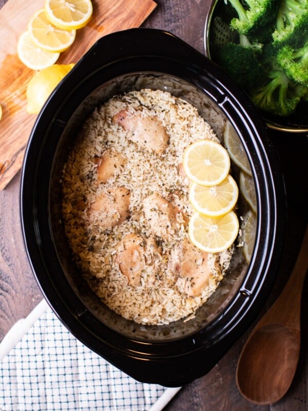 cooked rice and lemon chicken in a slow cooker with broccoli on the side.