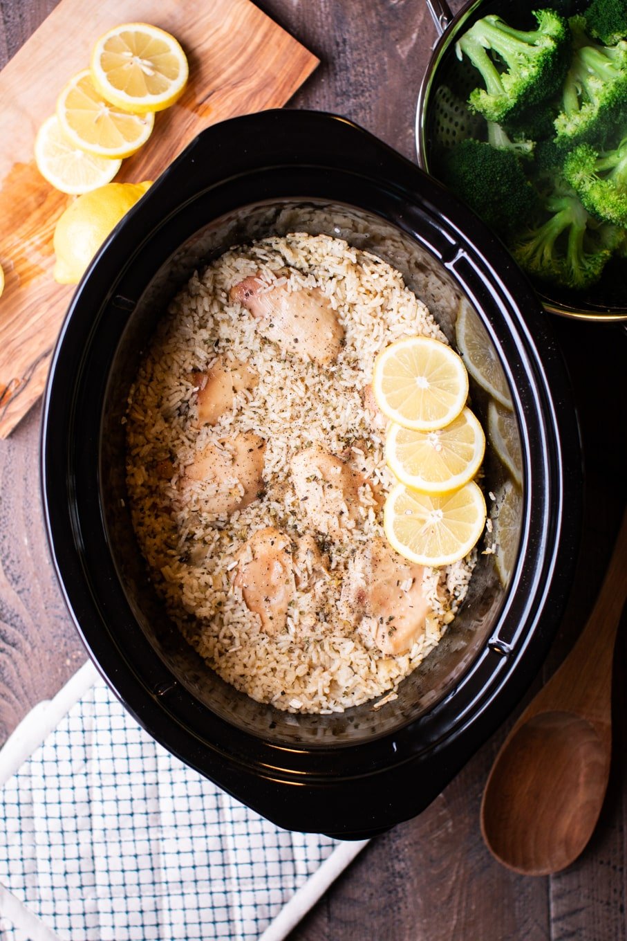 cooked rice and lemon chicken in a slow cooker with broccoli on the side.