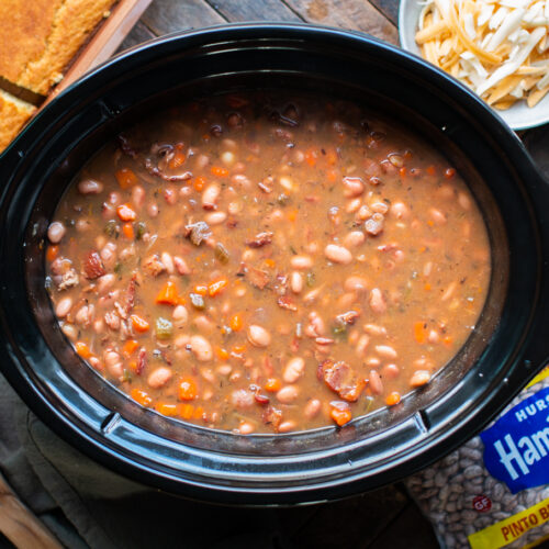 pinto beans cooked in slow cooker with cheese and cornbread on the side.