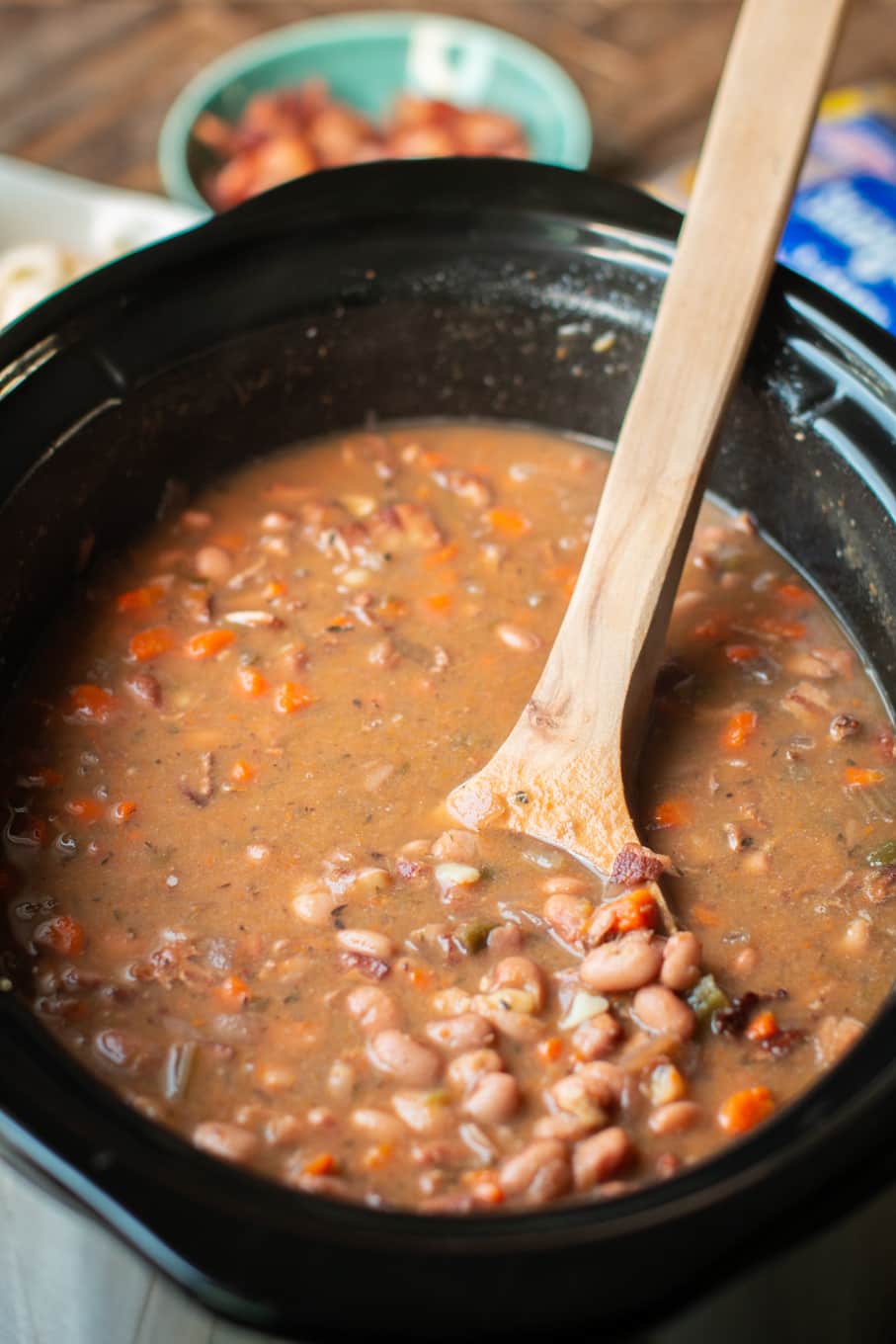 close up of pinto beans and bacon in a slow cooker.