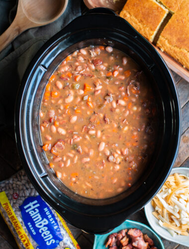 cooked pinto beans with carrots and bacon in a slow cooker.