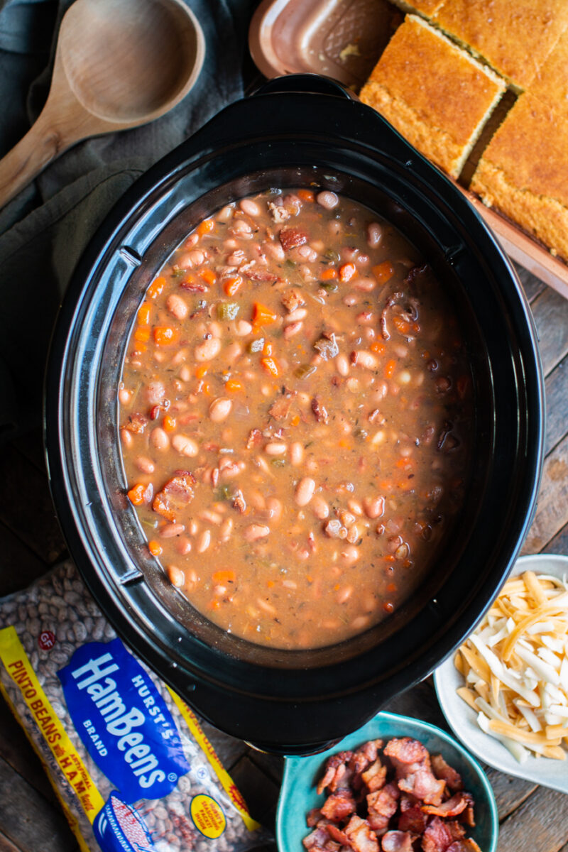 cooked pinto beans with carrots and bacon in a slow cooker.