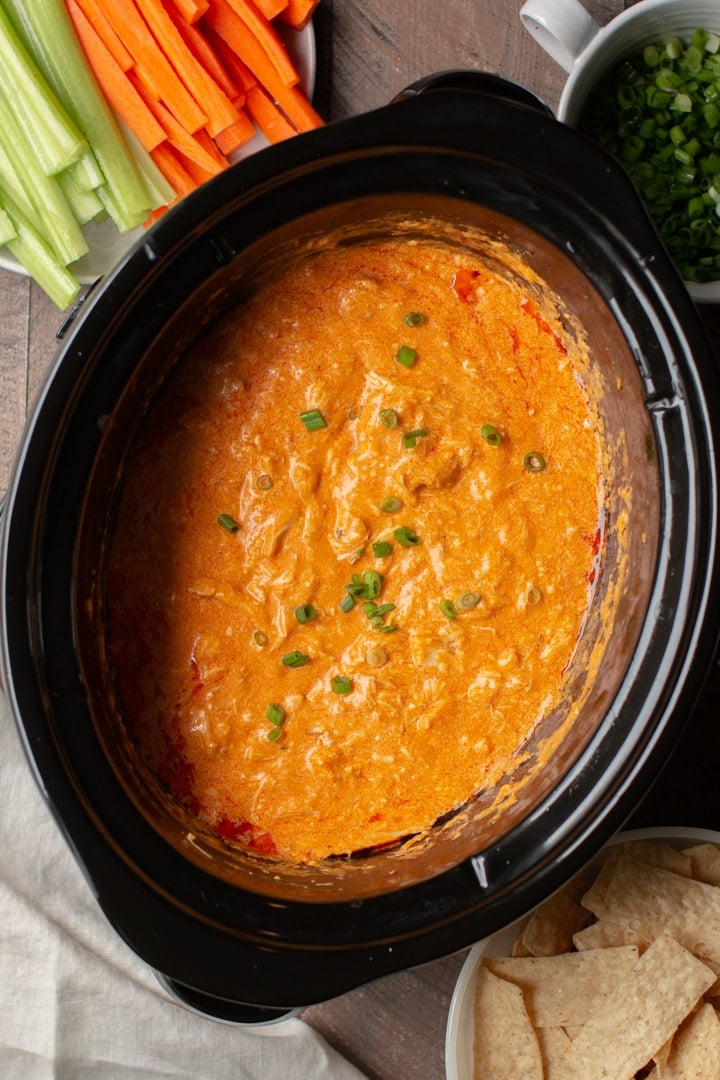 cooked buffalo dip in the slow cooker with carrots and celery on the side.