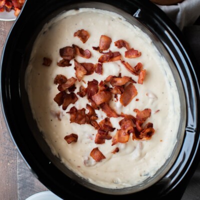 creamy potato soup with bacon on top in a slow cooker.