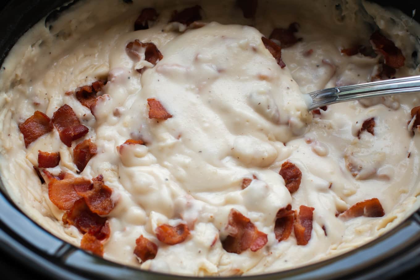 close up of potato soup with metal ladle.