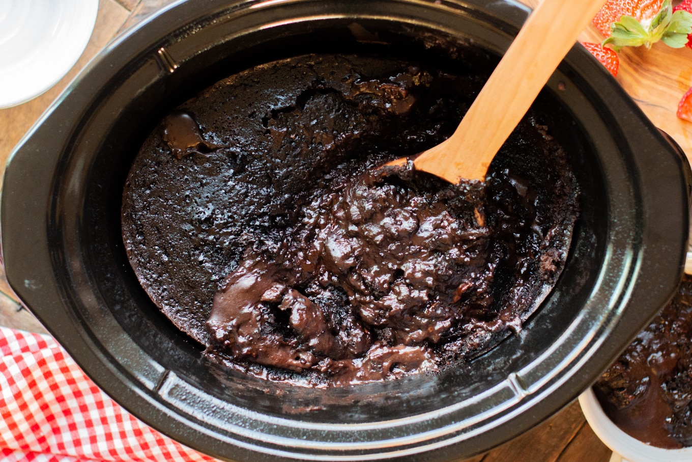 cooked lave cake in a slow cooker with red and white napkin on the side.