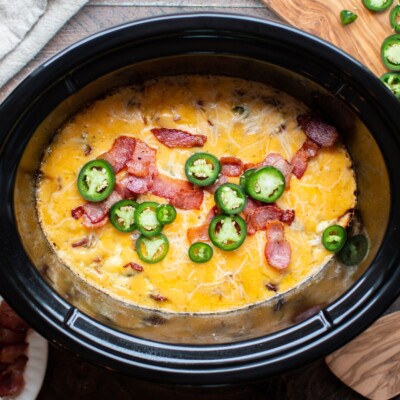 cooked egg casserole in a slow cooker with bacon and jalapenos on top.