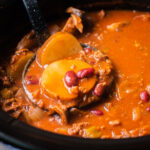 Tomato-based stew with potatoes and kidney beans on a ladle