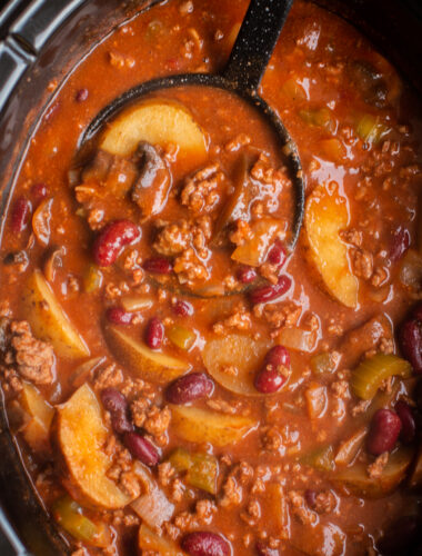 shipwreck stew cooked in a slow cooker with a black ladle.