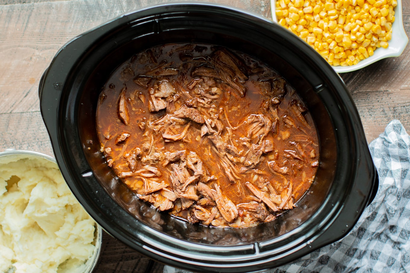 shredded beef in a slow cooker in a beer, onion ketchup sauce.