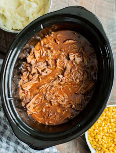 cooked shredded meat in a slow cooker in beef, onion and ketchup sauce.