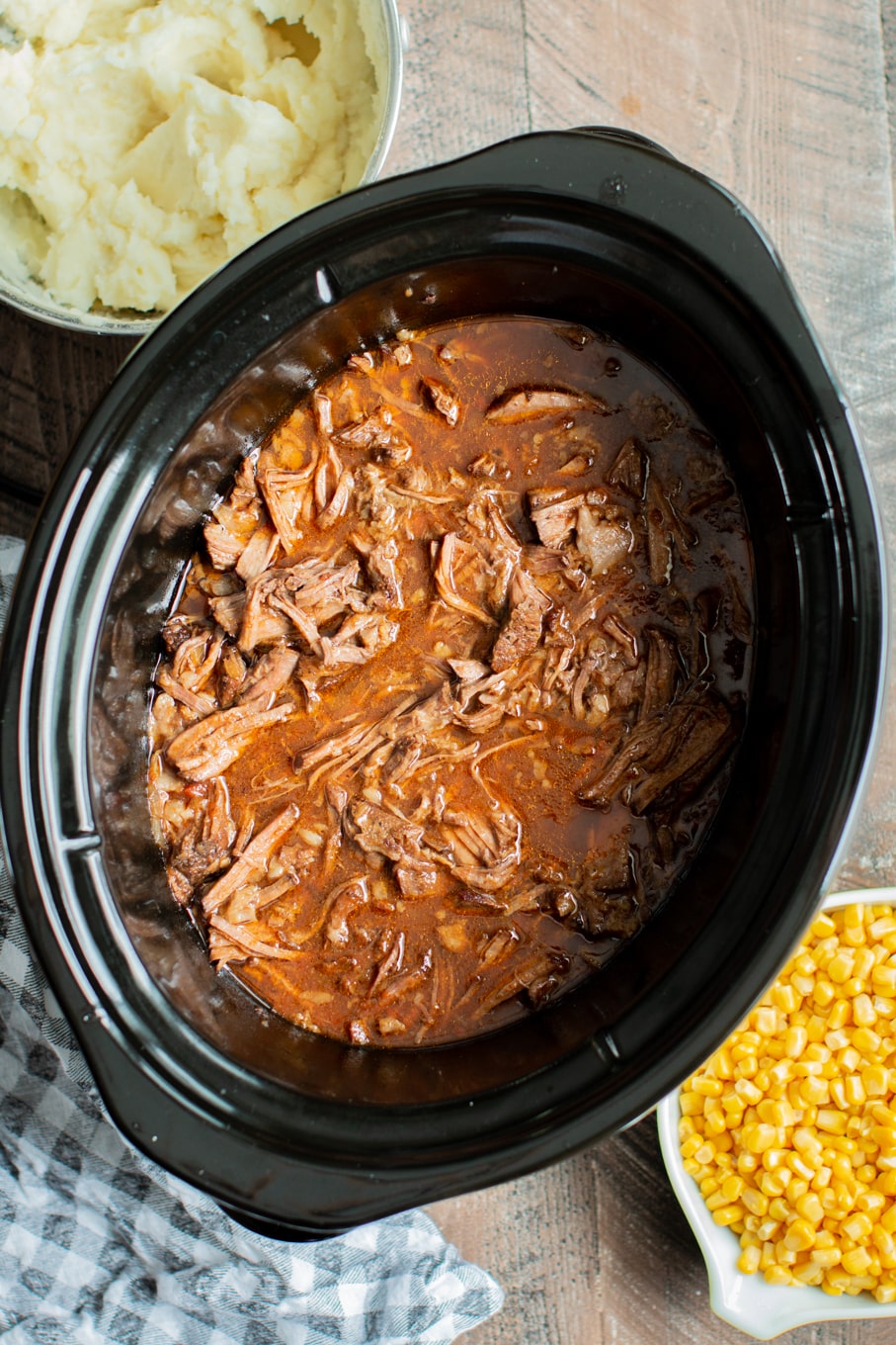 cooked shredded meat in a slow cooker in beef, onion and ketchup sauce.