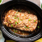 Pork loin with onion, sauce and sesame seeds in a slow cooker.