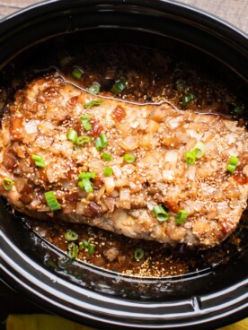 Pork loin with onion, sauce and sesame seeds in a slow cooker.