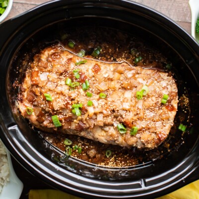 Pork loin with onion, sauce and sesame seeds in a slow cooker.