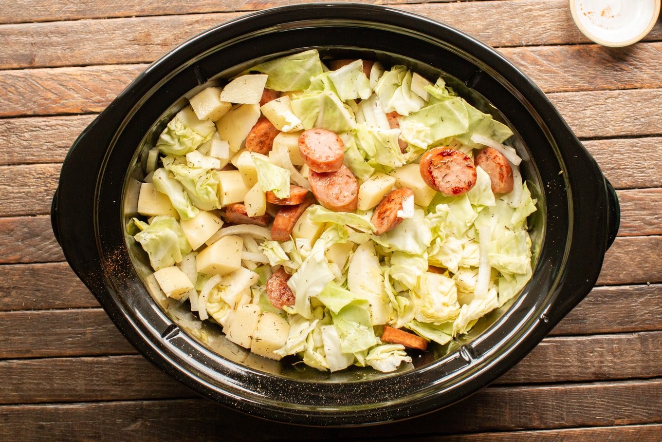 cabbage, potatoes, onions and kielbasa mixed together in a slow cooker.