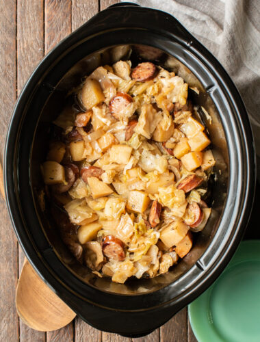 slow cooker with cubed potatoes, sliced kielbasa, and cabbage.