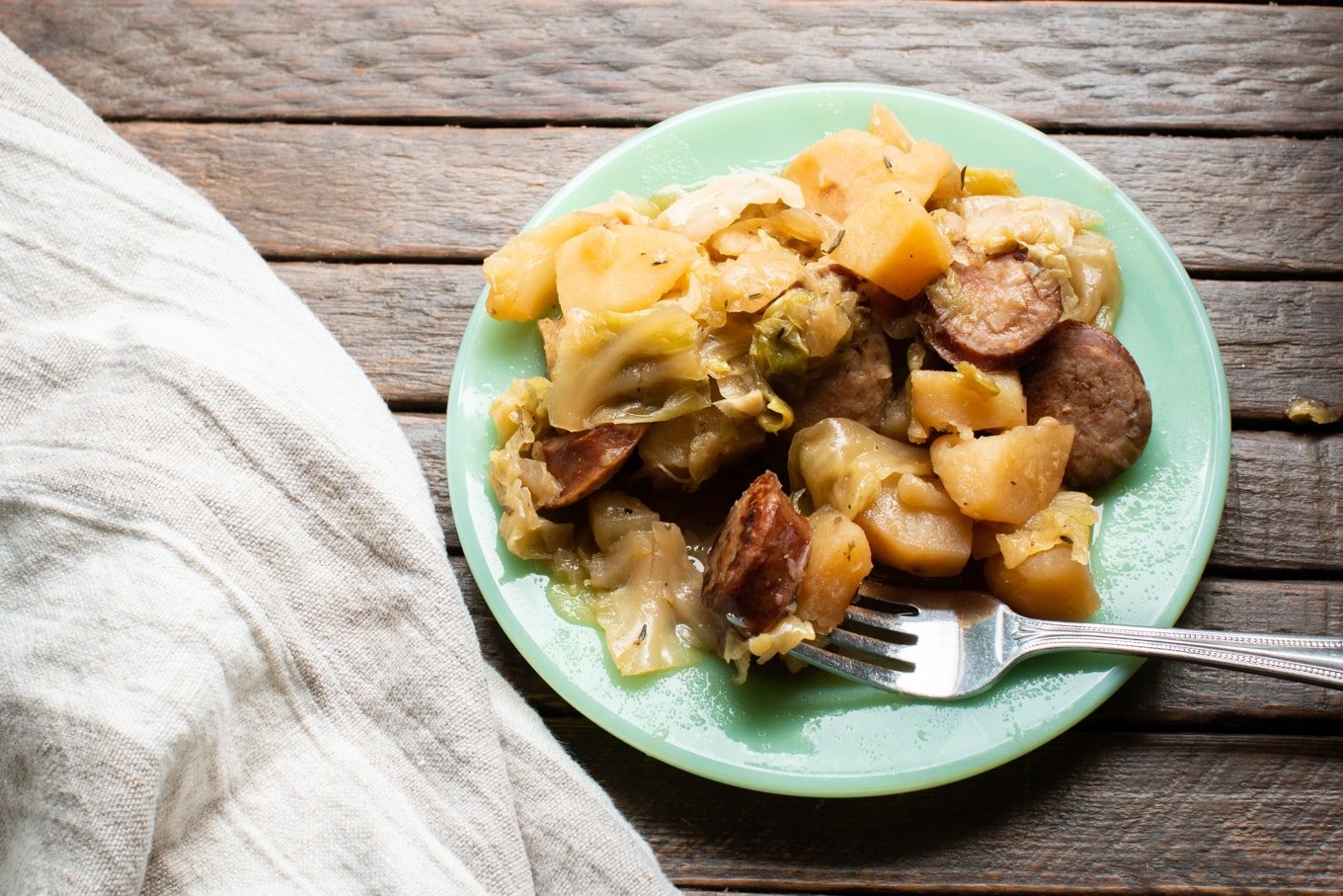 Plate with cooked kielbasa, potato and cabbage.