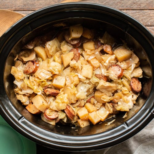 finished cooking potatoes, kielbasa and cabbage in an oval slow cooker.