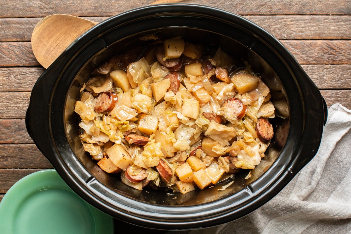 finished cooking potatoes, kielbasa and cabbage in an oval slow cooker.
