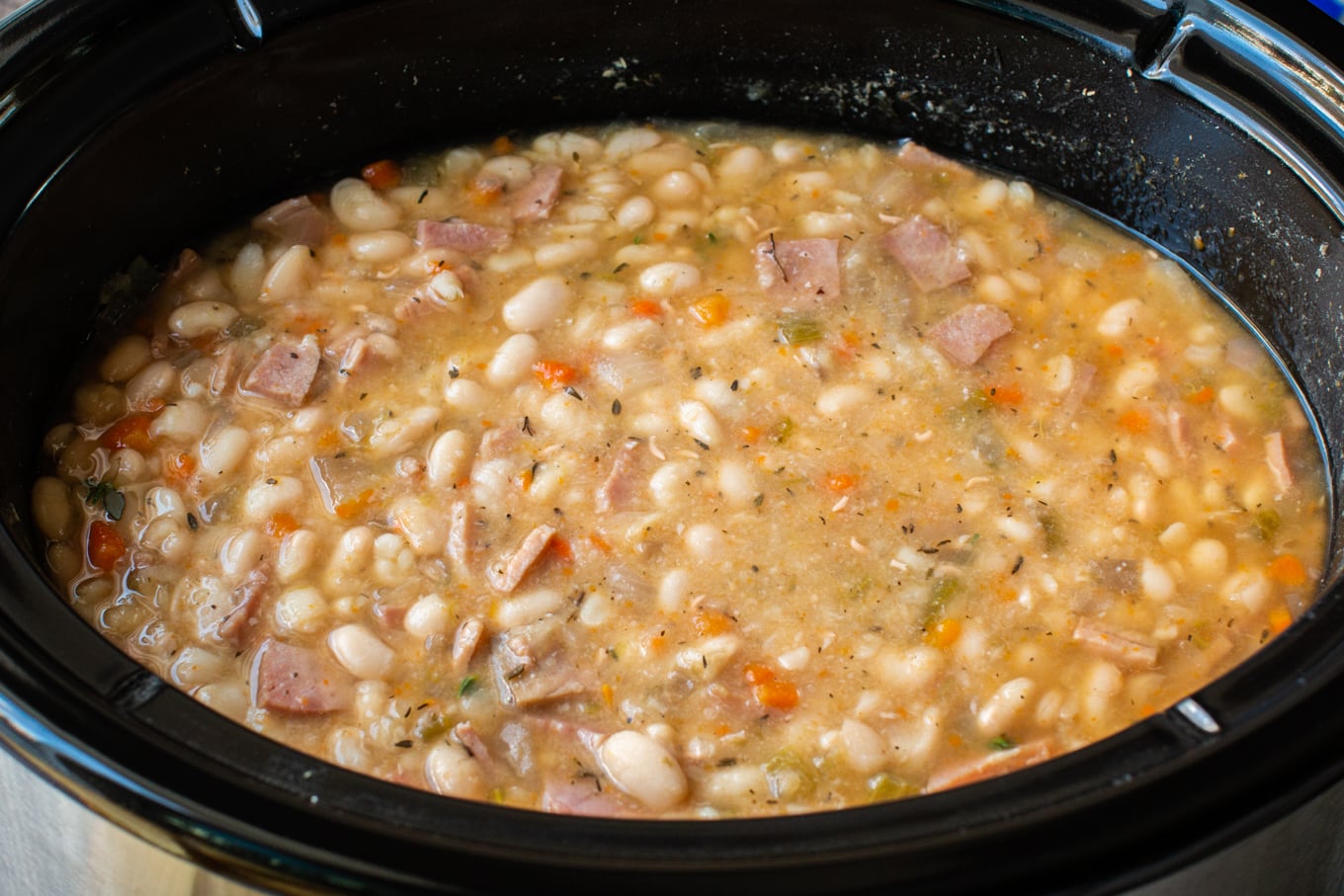 close up of beans and ham soup in a slow cooker.