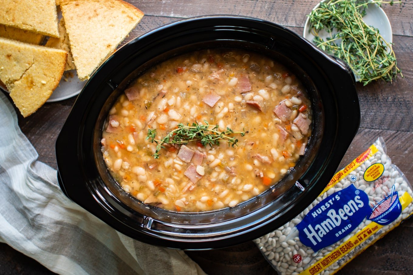 finished ham and beans in crockpot with thyme in the middle for garnish.