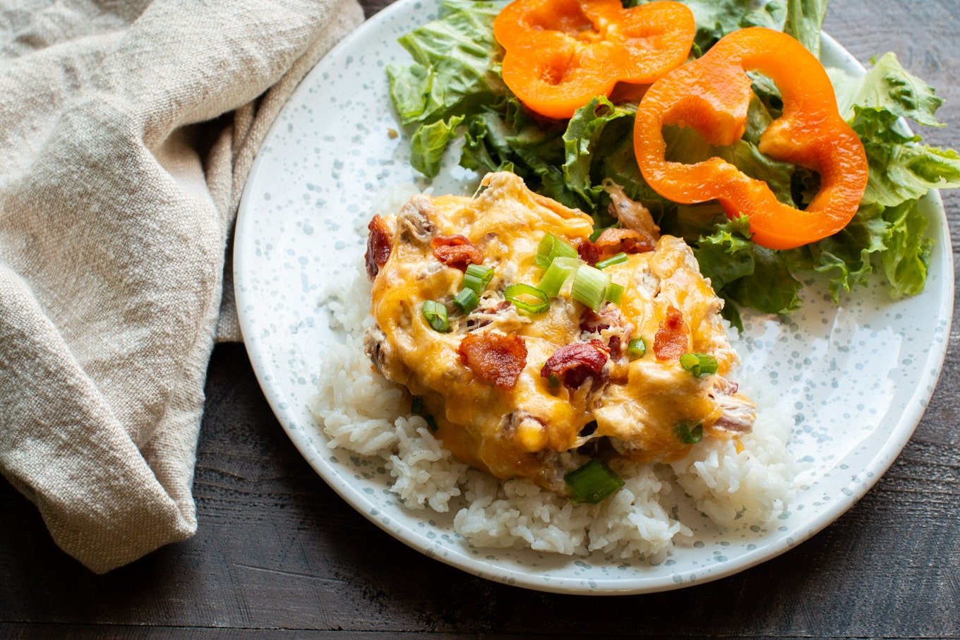 crack chicken over rice with salad on side on speckled plate