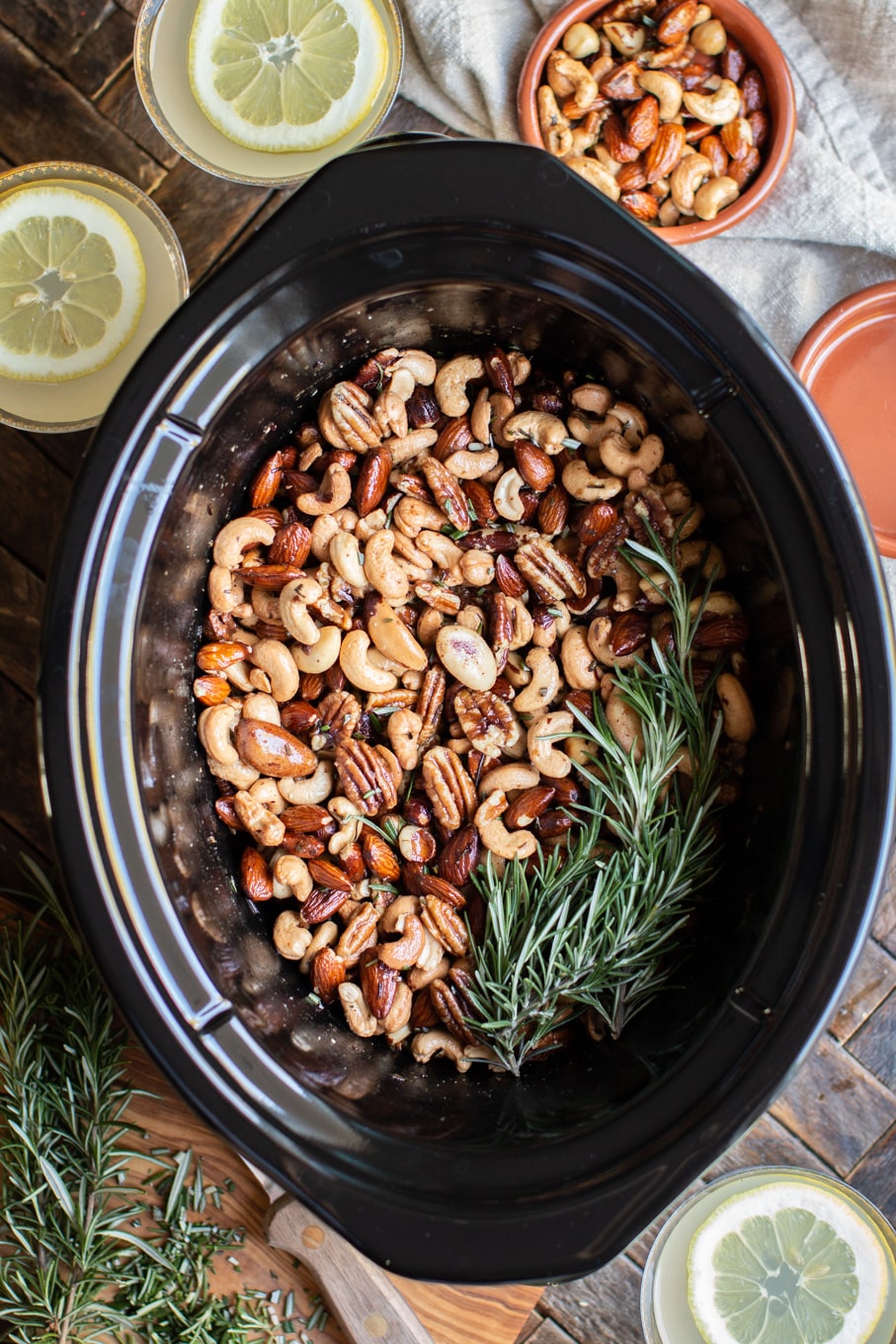 mixture of nuts in the slow cooker with rosemary sprig