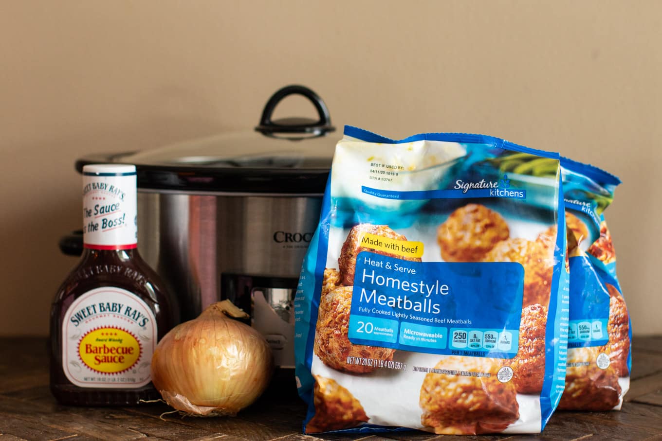 Bag of meatballs, barbecue sauce and onion in front of a slow cooker.