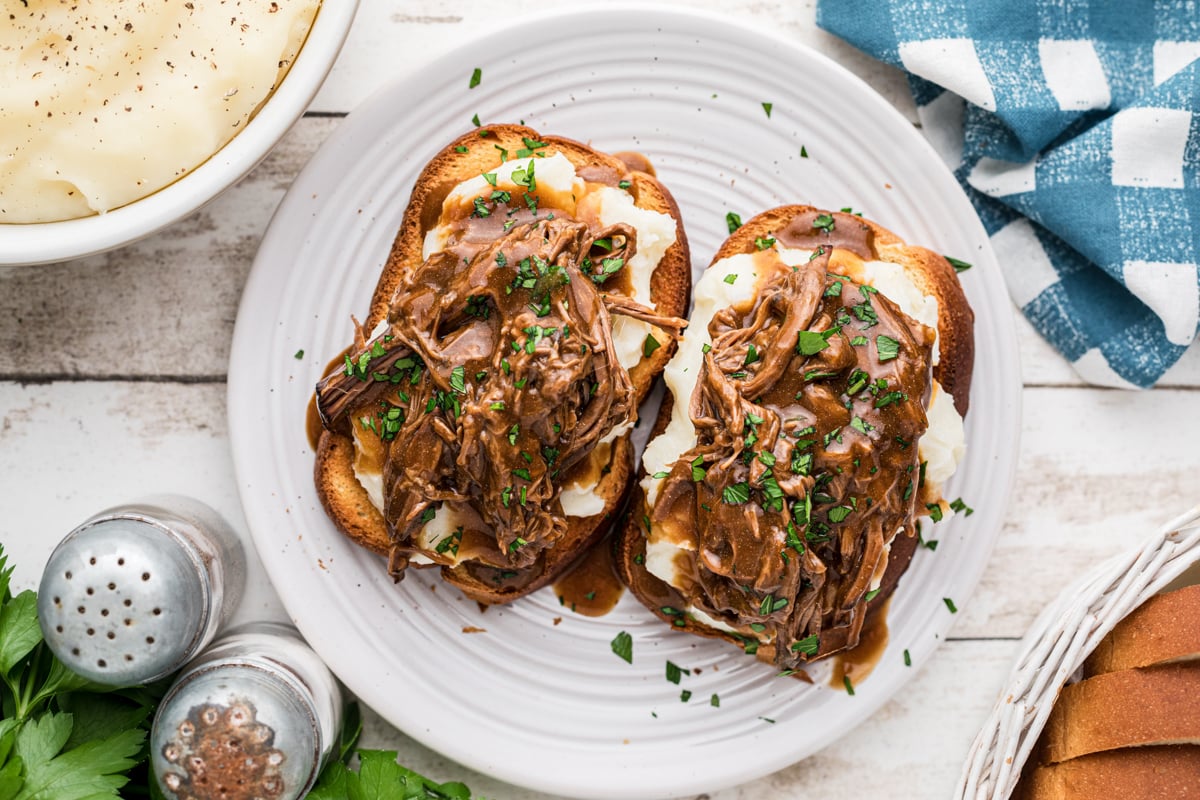 Overhead shot of hot roast beef sandwiches on a plate.