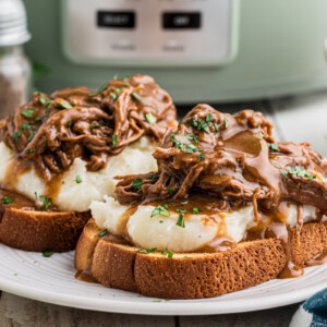 2 hot roast beef sandwiches on a plate.