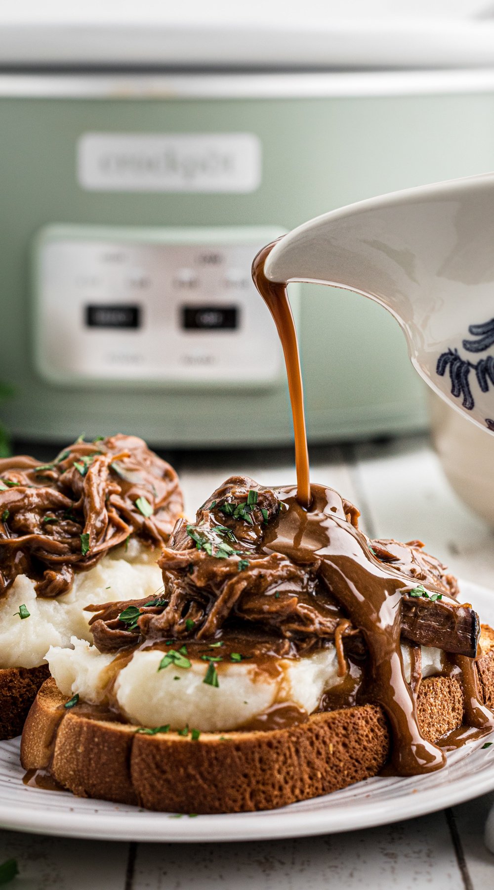 long image of hot roast beef sandwiches with gravy being poured over.