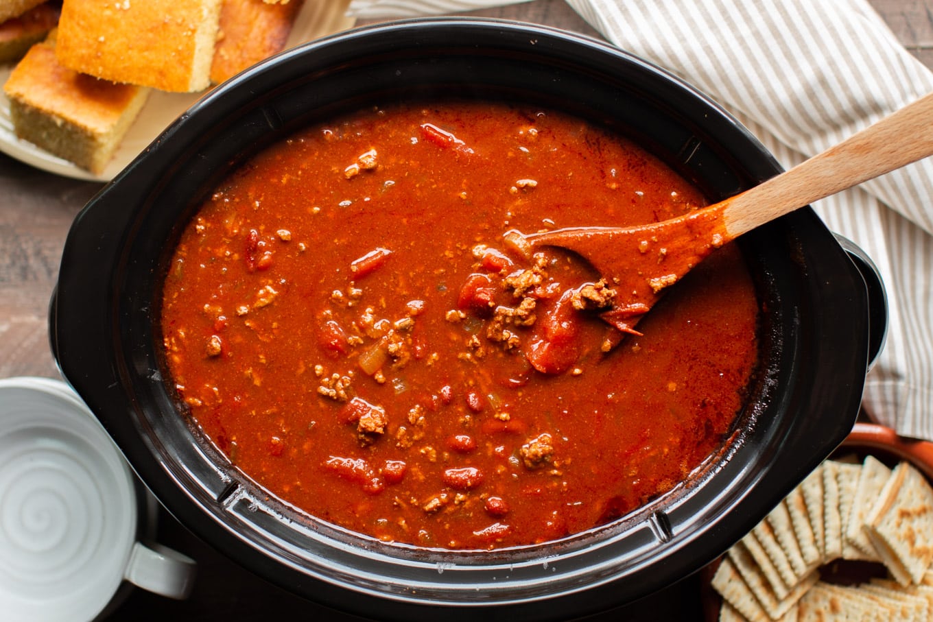 finished cooking v8 chili in a slow cooker with wooden ladle in it.