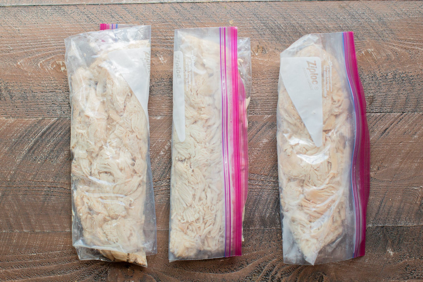 3 ziplock bags ready for the freezer with shredded chicken in them.