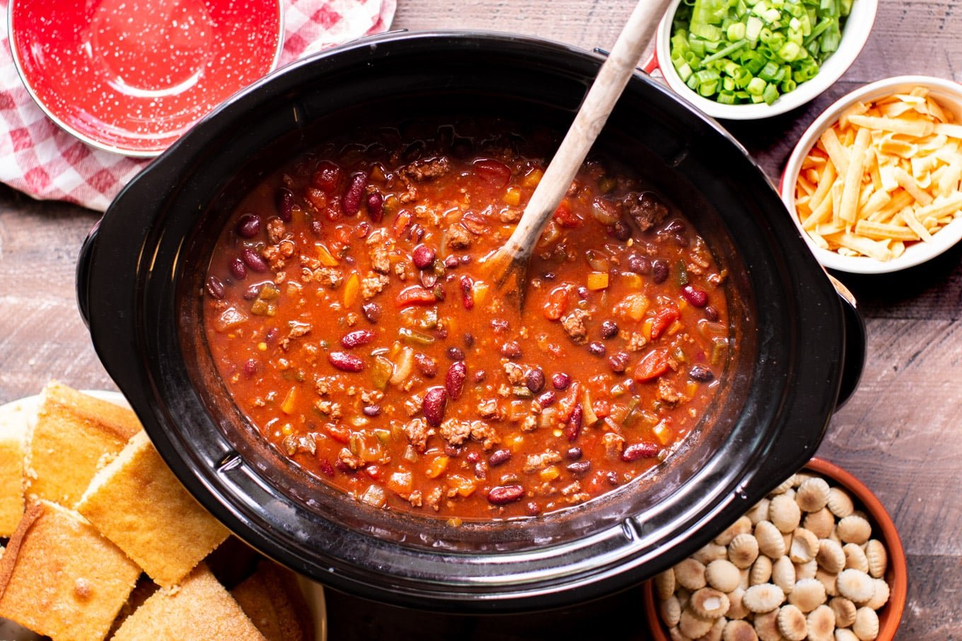 Finished cooking venison chili in a slow cooker with a wooden spoon in it.