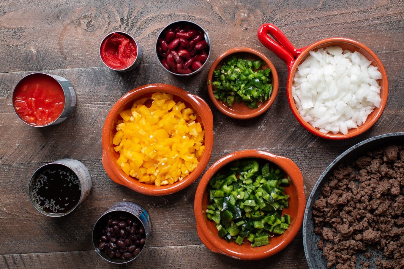 Can of beans, dished full of peppers and onions. Skillet with cooked ground venison in it.