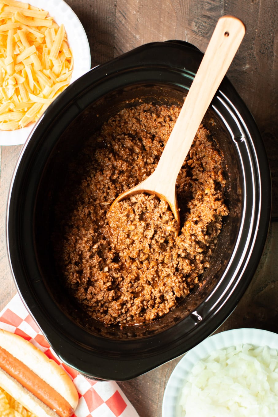 chili for hot dogs in a slow cooker. Cheese and onions on the side.