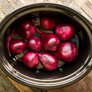 Cooked and peeled beets in an oval slow cooker.