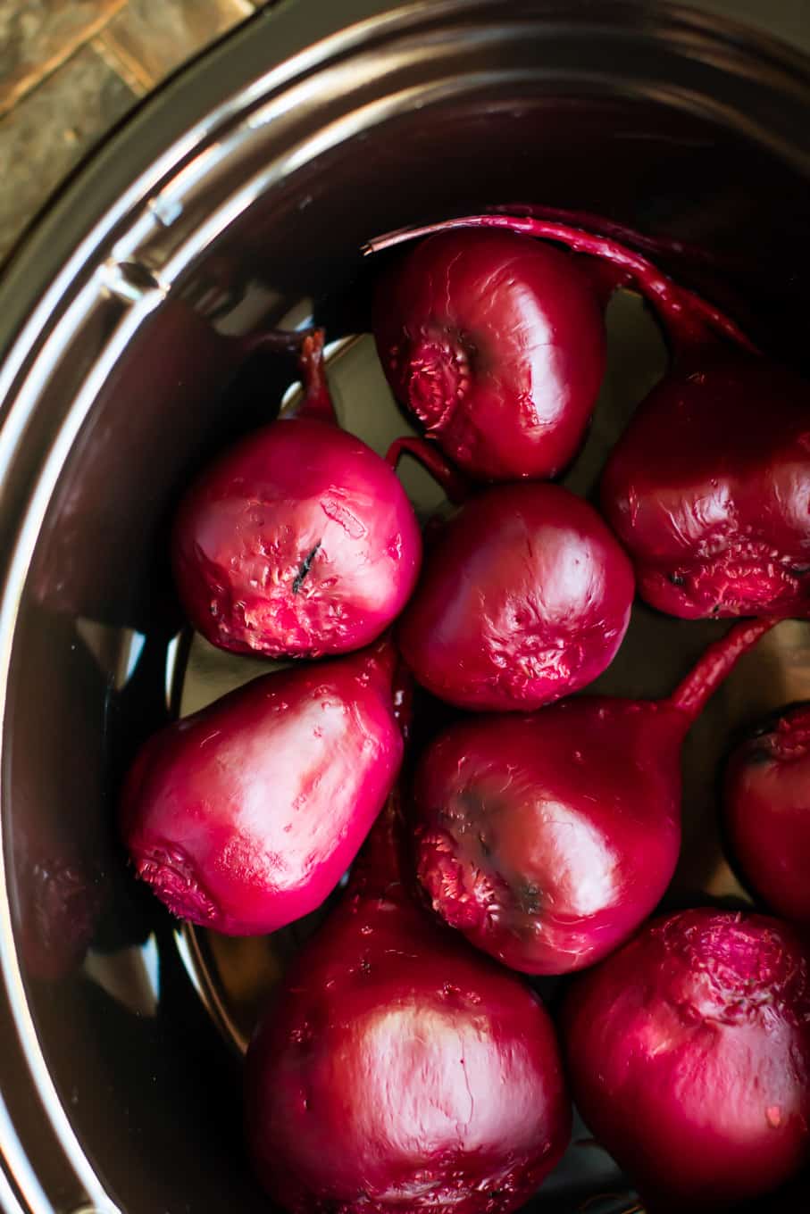 close up of brightly burgandy colored beets in a slow cooker.