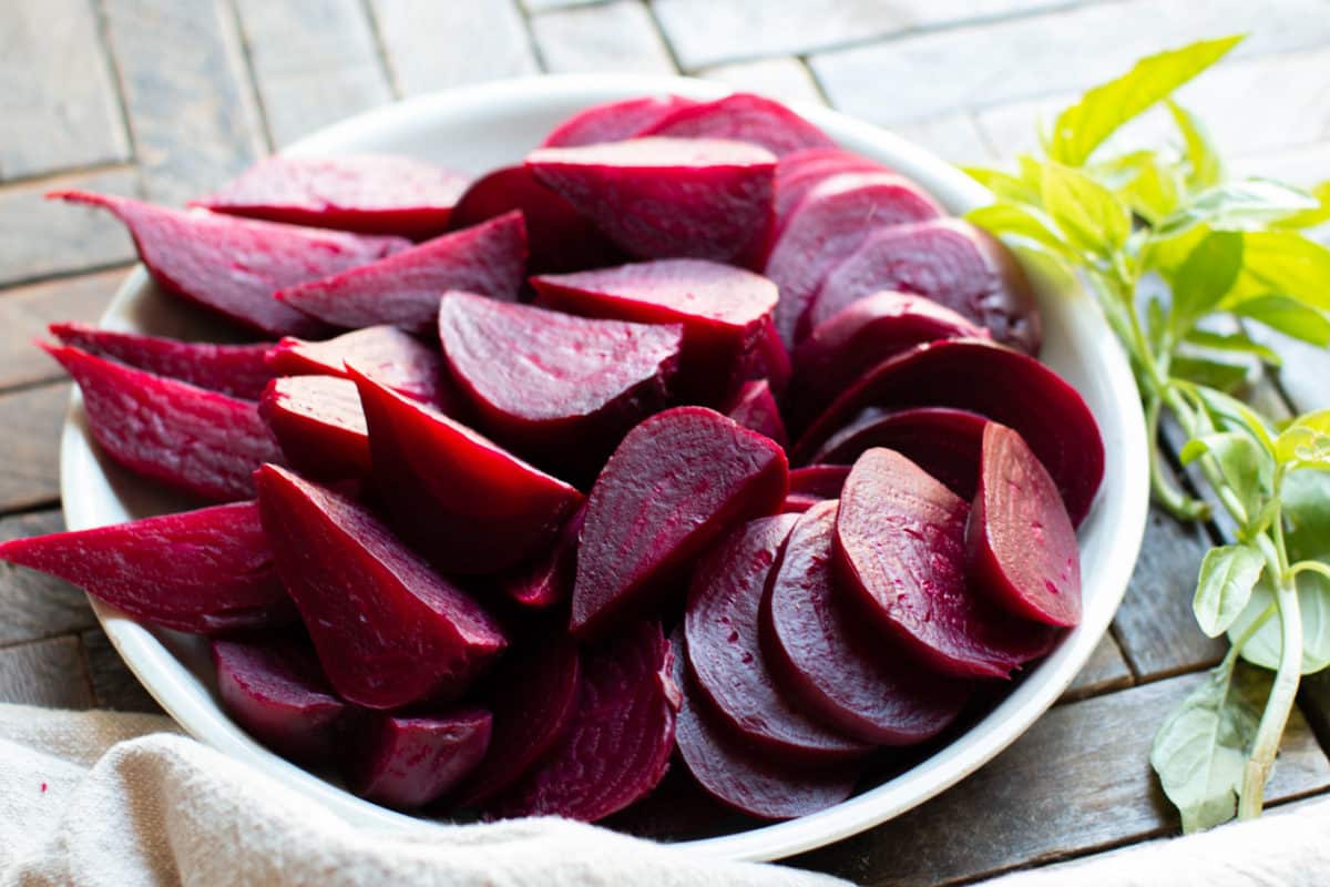 sliced beets on a plate with basil on the side.