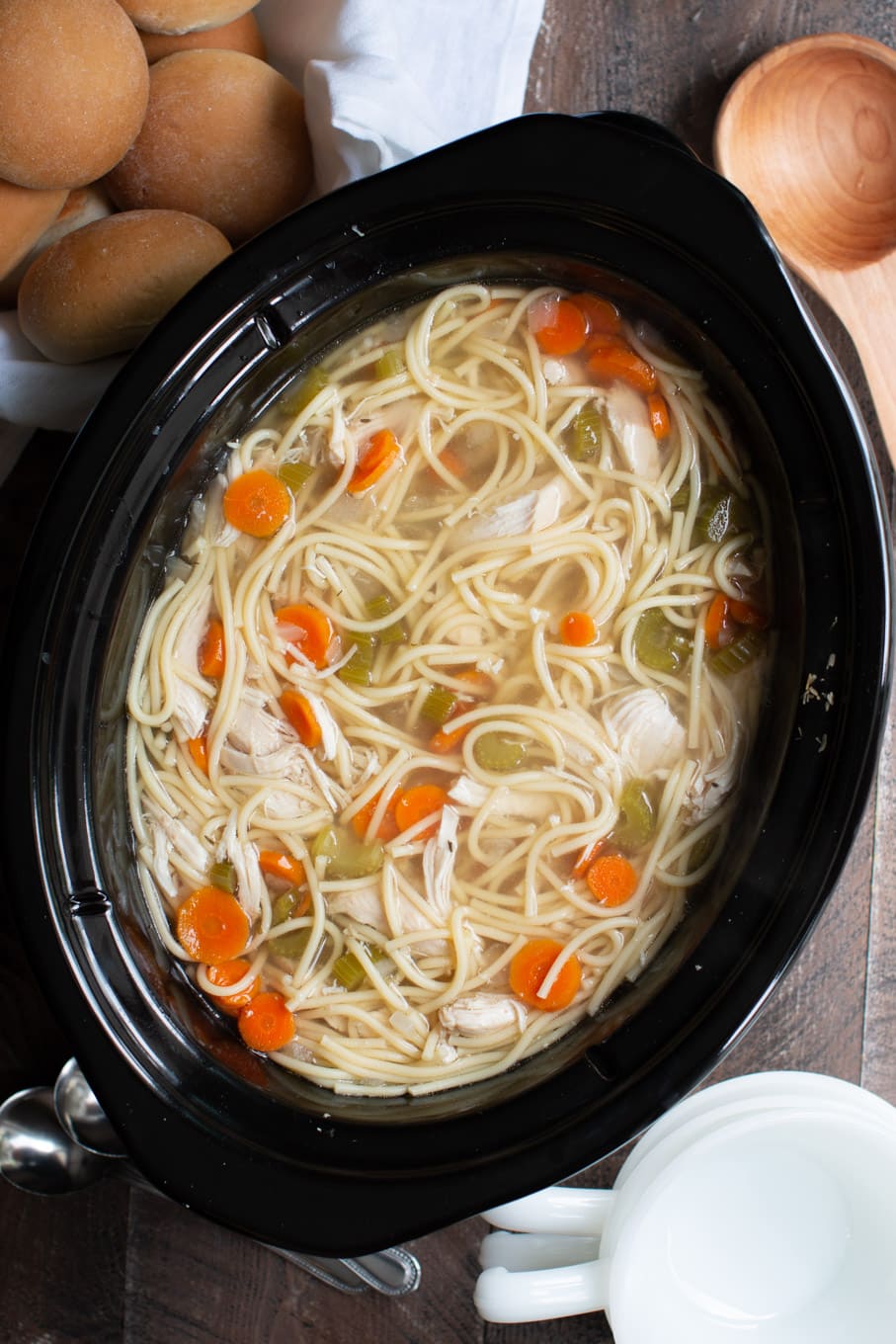 Chicken noodle soup in a slow cooker with spaghetti type noodles, carrots and celery.