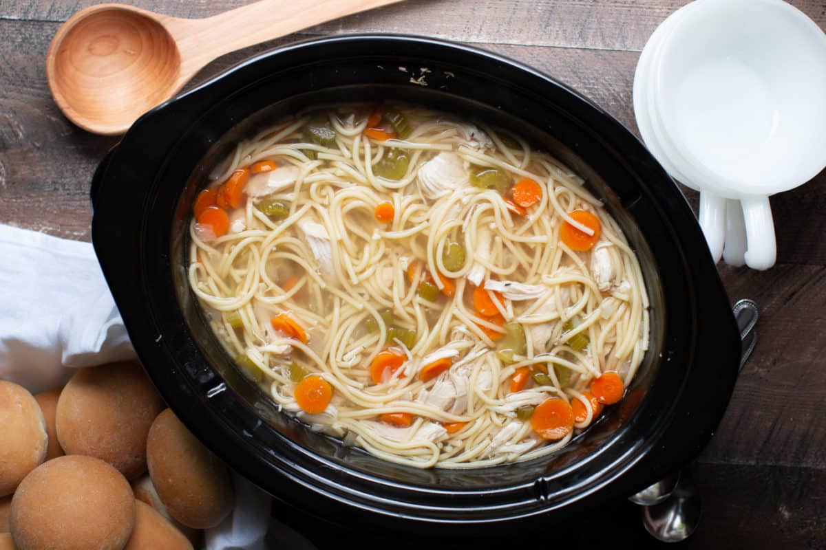 finished cooking chicken noodle soup with rolls on the side.