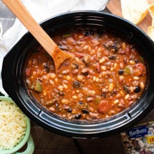 cooked pizza bean soup in a slow cooker with mozzarella cheese and garlic bread on the side.