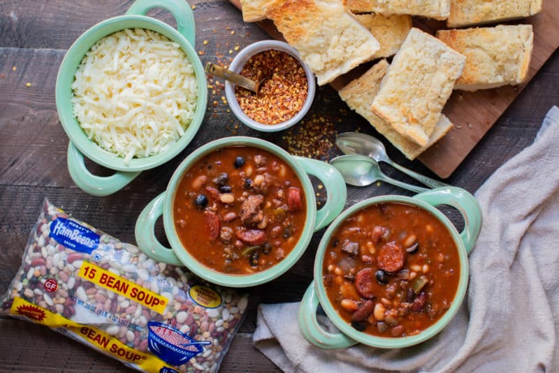 2 bowls of pizza bean soup in teal bowls. Bag of 15 bean soup mix next to it.