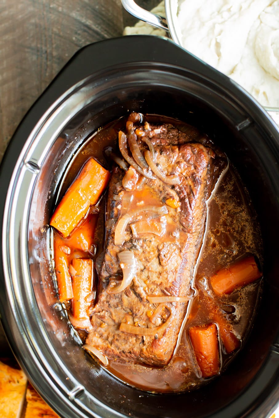 cooked brisket in the slow cooker with carrots and onions.