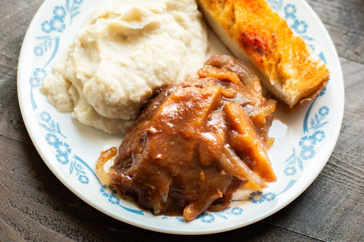 white plate with mashed potatoes, apple butter pork chops and garlic bread 