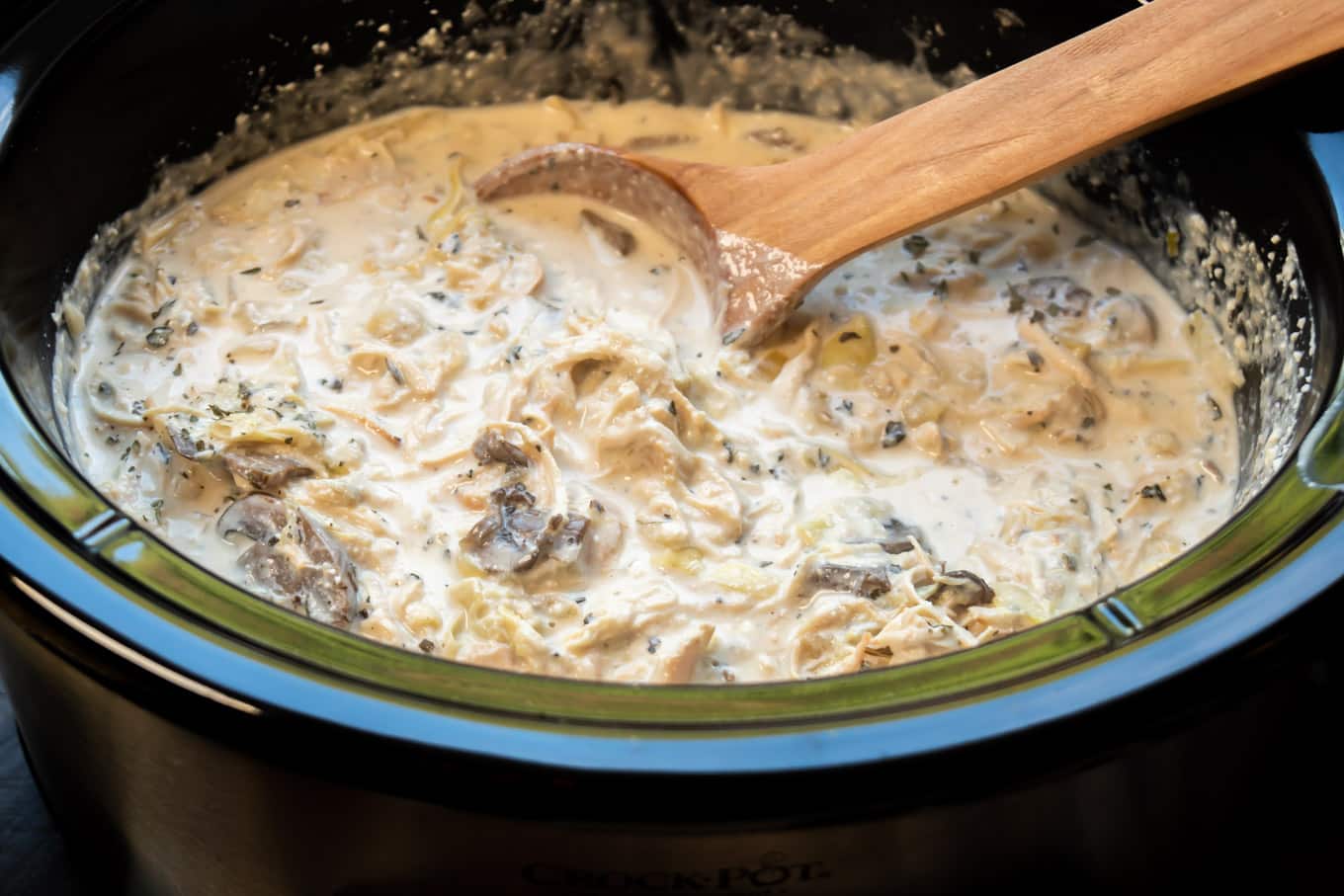 Artichoke mushroom chicken ready to serve with wooden spoon