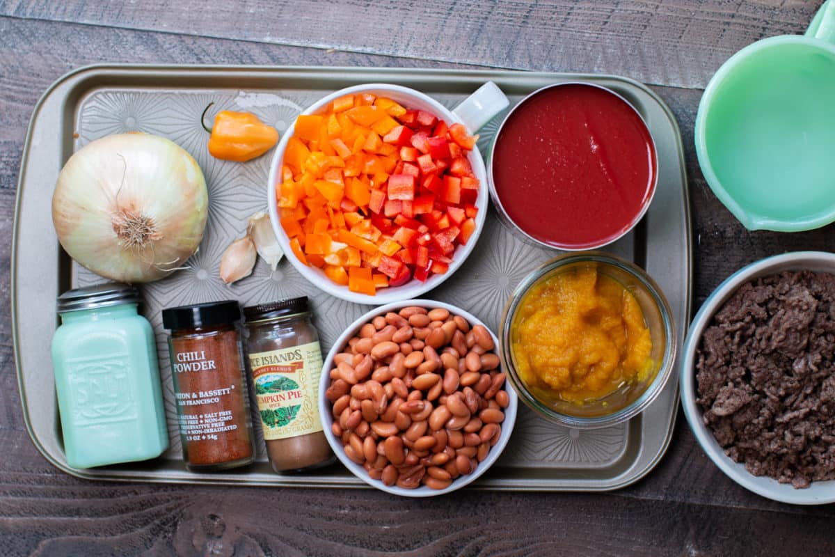 tomato sauce, bell peppers, pinto beans, seasonings, pumpkin puree, onion and habanero on a pan.