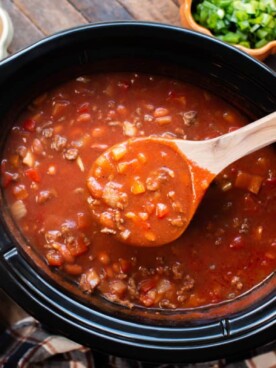 ladle scooping pumpkin chili from a slow cooker.